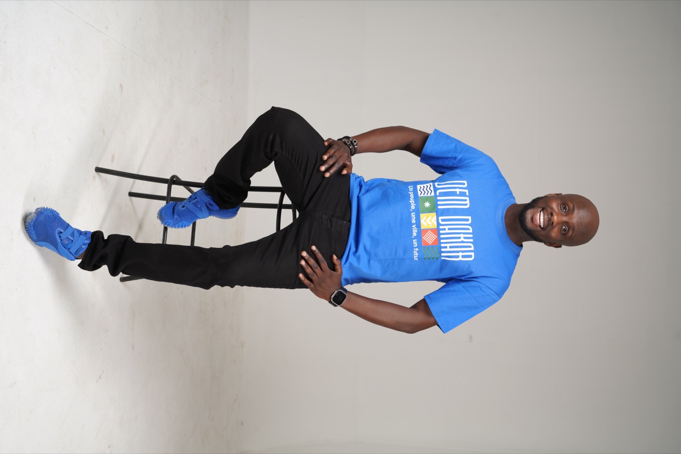 Modèle assis portant le t-shirt DEM DAKAR bleu