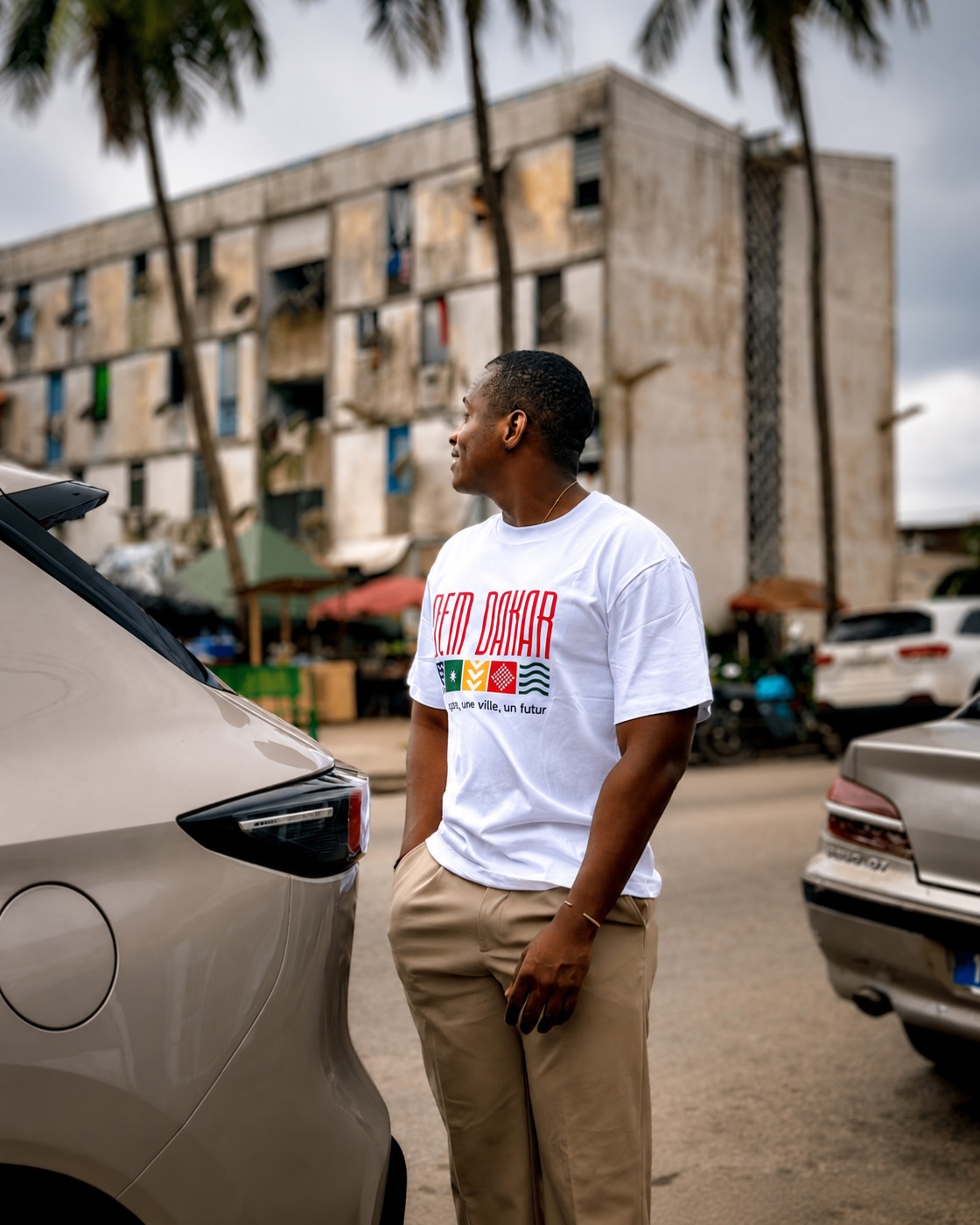 Homme portant le t-shirt DEM DAKAR blanc dans la rue à Dakar